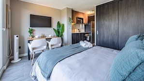 A compact hotel room with a bed, a desk, and a kitchenette. - M&C Departamento Irarrazaval 614 (Santiago)