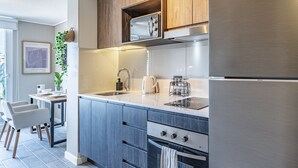 A modern kitchen with stainless steel appliances, wooden cabinets, and a built-in oven. - M&C Departamento Irarrazaval 614 (Santiago)
