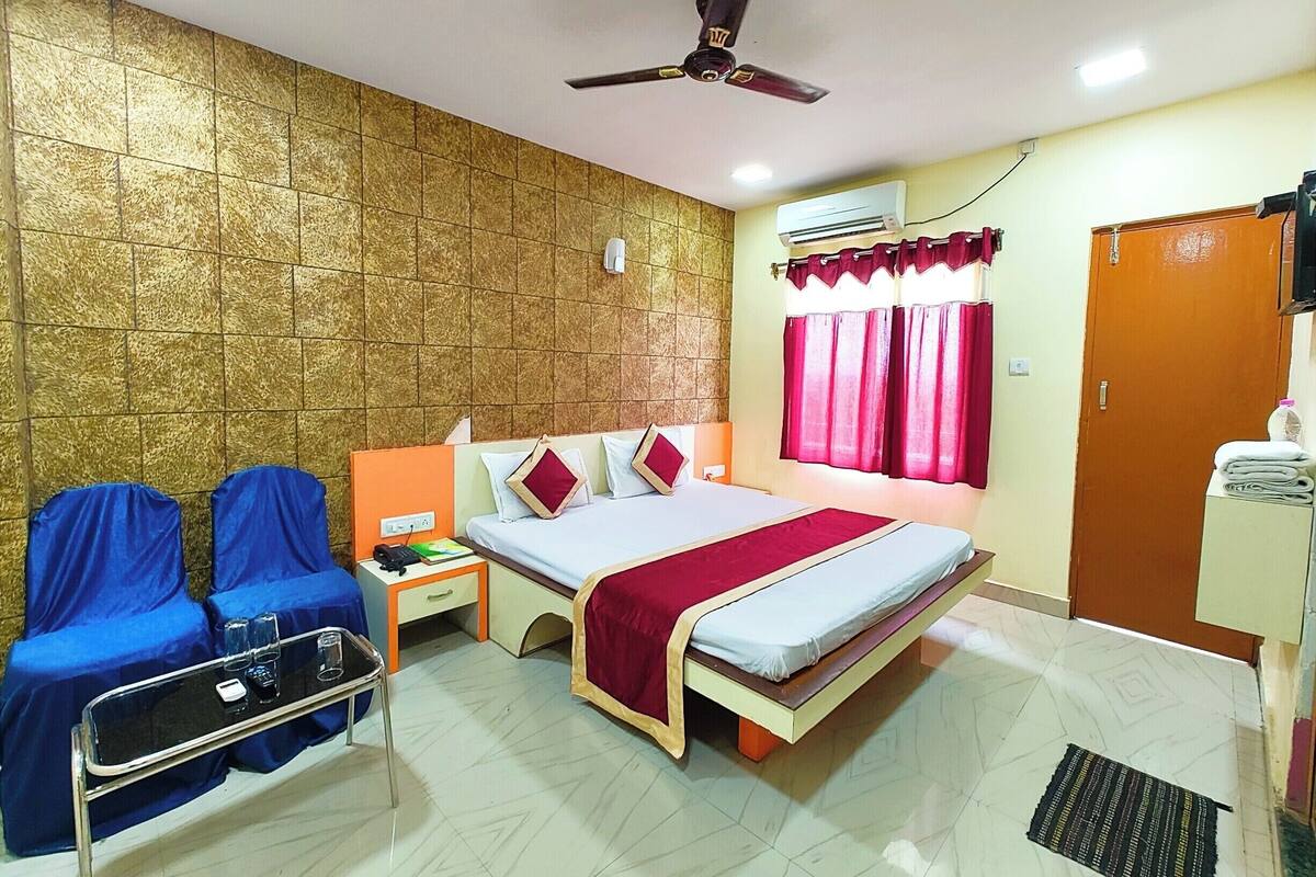 Una habitación de hotel con cama, mesita de noche, silla, aire acondicionado y armario.
