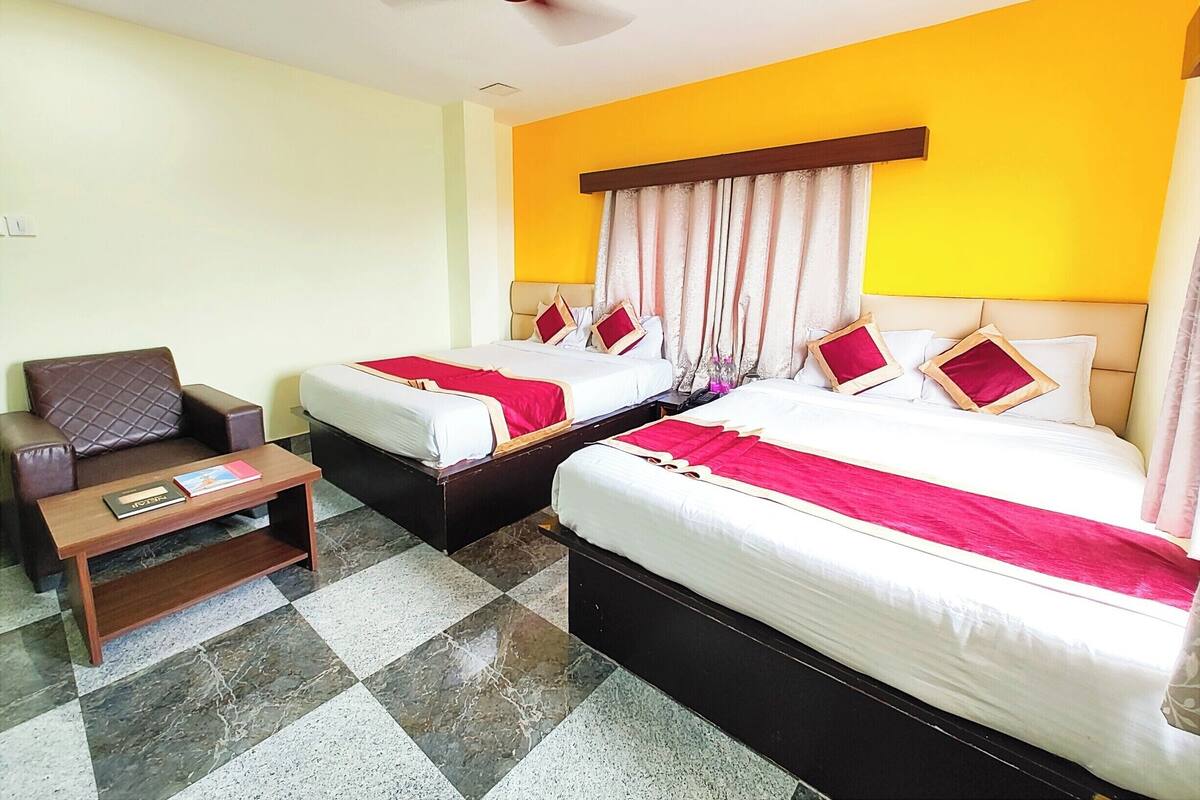Una habitación de hotel con dos camas, un sofá, una mesita y un ventilador de techo.