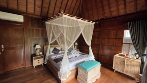 A wooden room with a four-poster bed, a nightstand, a bedside table, and a wooden cabinet.