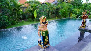 A pool with statues of figures in traditional attire.
