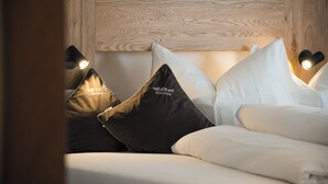 A bed with white and brown pillows, a wooden headboard, and two bedside lamps. - Brixen-Plose! Your spacious family apartment directly in St. Andrä (Sankt Andrä)