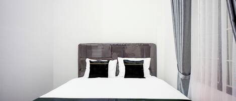 Un lit bien fait, avec une couvre-lit noire et blanche, deux oreillers et une tête de lit.