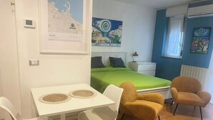 Une chambre à coucher avec un lit, un bureau avec deux chaises, une carte et un tableau.