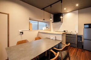Een kleine keuken met een eethoek, houten stoelen, een grijze tafel en een inbouwoven.