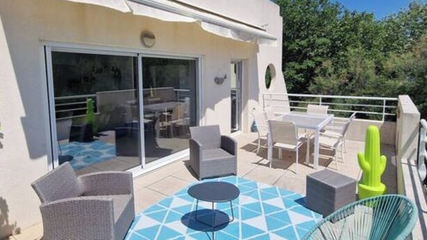 Eine Terrasss mit Korbmöbeln, einem runden Tisch und einer Kakteendekoration.