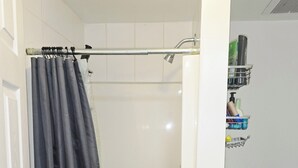 A bathroom with a shower, toilet, and a shelf with toiletries. - Private bedroom (2) in shared suit (Delta)