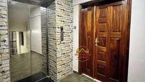 Un couloir avec un mur en pierre, une porte en bois et un ascenseur en verre.