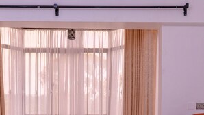 Une fenêtre avec des rideaux légers et un luminaire décoratif suspendu.