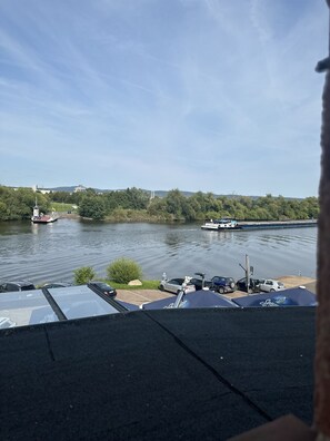 A riverside view with boats, a dock, and parked cars. - Hotel Mainchateau (Seligenstadt)