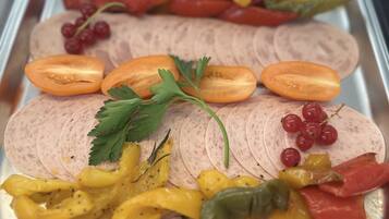 Ein Tablett mit geschnittenem Fleisch, garniert mit Tomaten, Paprika und Kräutern.