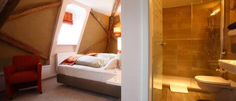 Un dormitorio con cama, una silla roja y una ventana con cortinas.