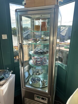 A refrigerated display case with multiple shelves containing various food items. - Hotel Mainchateau (Seligenstadt)
