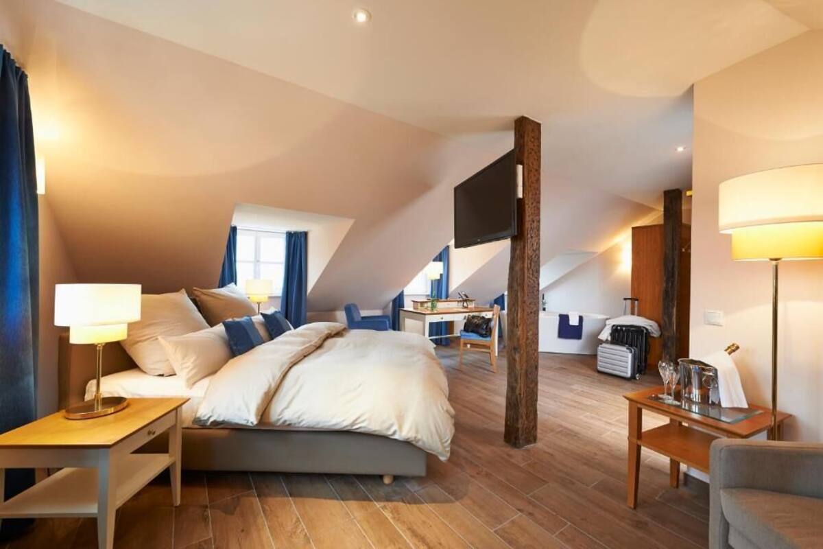 Ein modernes Hotelzimmer mit einem großen Bett, einem Schreibtisch, einem Stuhl und einem Fernseher.