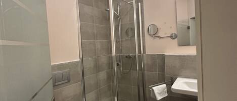 Un baño moderno con ducha de mampara de vidrio, inodoro y lavabo.