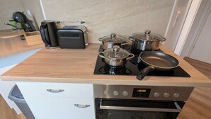 A kitchen with a built-in oven, a coffee maker, and two electric kettles on a wooden countertop. - 2 room apartment touring view at the Kaiserberge motorcycle / bicycle garage (Waldstetten)