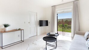 A modern living room with a sofa, a coffee table, a TV, and a view of the outdoors.