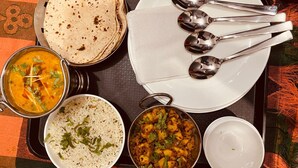 Een tafel met diverse gerechten, waaronder een kom rijst, een curry en een bord platbrood.