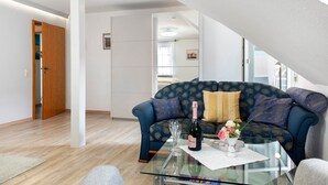 A living room with a glass coffee table, a sofa, a door, and a staircase.
