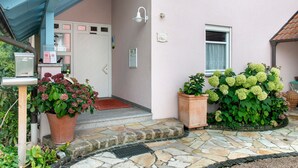 A building with a stone entrance, a mailbox, a light fixture, and potted plants.