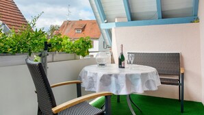 A round table with a white tablecloth, two chairs, a bottle of wine, and a glass on the table.