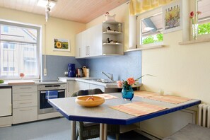 A kitchen with a built-in oven, a sink, and a dining area with a table and chairs.