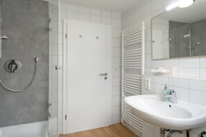 Un baño moderno con ducha, lavabo y espejo.