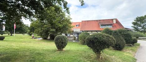 Een huis met een rood dak, omgeven door een verzorgd gazon en enkele struiken.