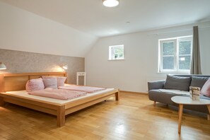 Una habitación con cama, sofá, una mesita y ventana.