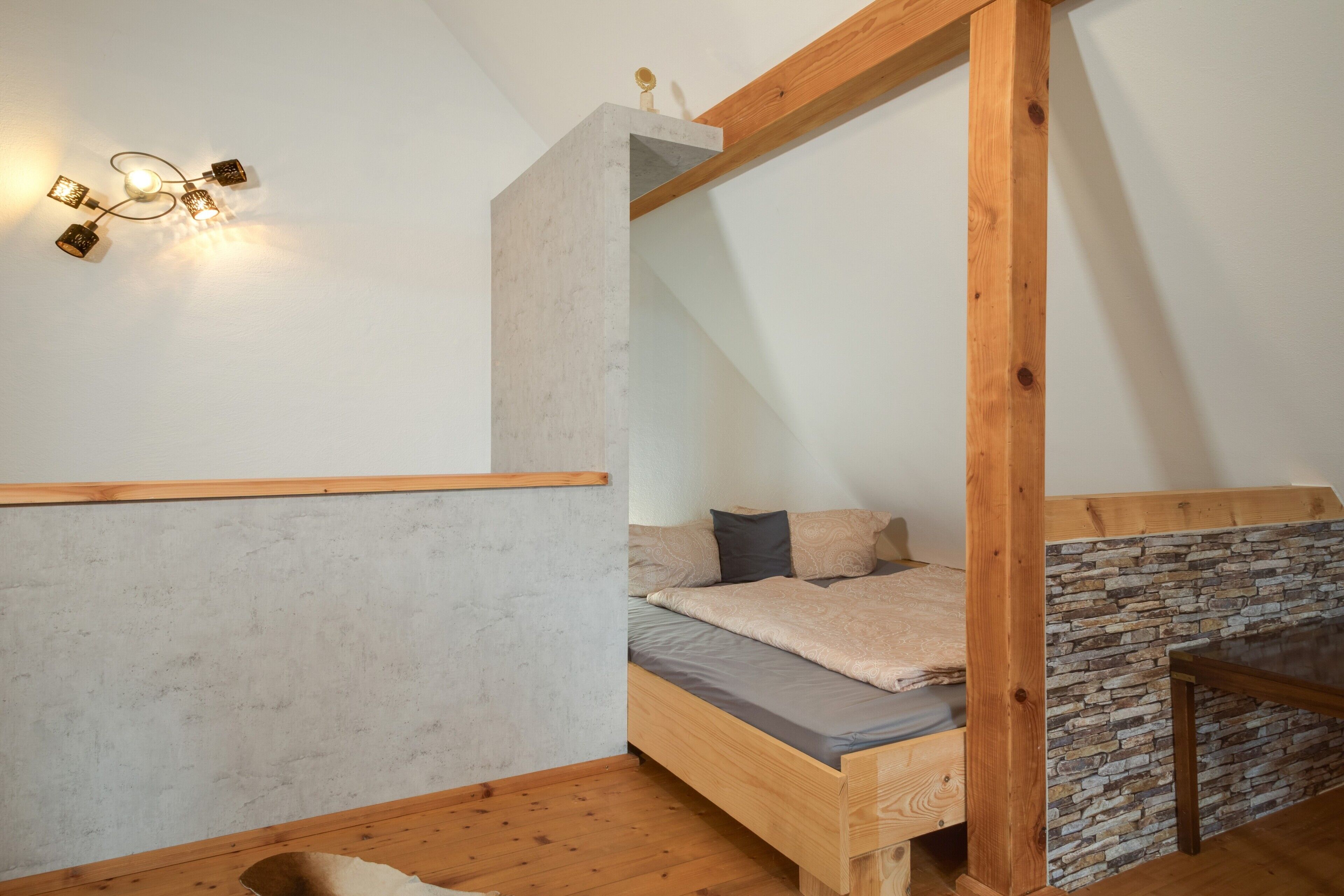 Ein Schlafzimmer mit Stockbett, einer Wand aus Steinplatten und einem Holzbalkenbau.