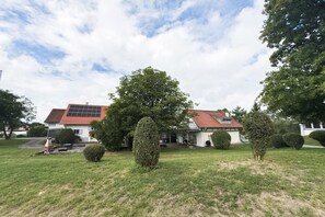 Ett hus med ett rött tak, omgivet av välskötta gräsmattor och träd.