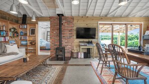 Un salon chaleureux avec une cheminée, des étagères en bois, un téléviseur et un coin repas.