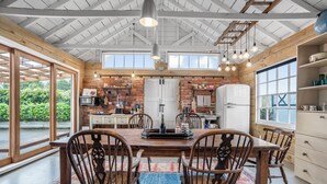 Une cuisine spacieuse dotée de meubles en bois, d’un grand îlot central et d’un coin repas avec une table et des chaises en bois.