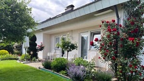 Ein Haus mit Garten, Rasen und weißer Gartenmöbeln.