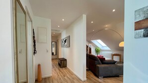 Ein modernes Interieur mit Holzboden, einer Couch, einer Lampe und einem Oberlicht.