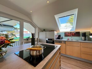 Uma cozinha moderna com ilha, forno embutido e claraboia.