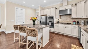A modern kitchen with white cabinets, stainless steel appliances, and a central island with bar stools. - 🦩Book Me Baby! Wild Blue Yonder at Blue Mountain Beach🦩 (Seagrove Beach)