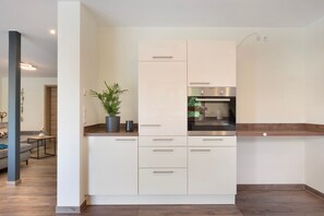 Una cocina moderna con armarios blancos, horno empotrado y una planta en maceta sobre la encimera.