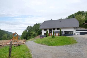A house with a driveway, a wooden play structure, and a garage.