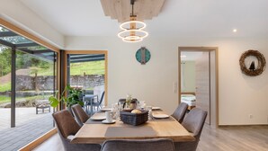 A dining area with a wooden table, grey chairs, a clock, and a view of the outdoors.