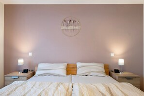 Una cama doble con cabecera de madera, dos mesitas de noche con lámparas y un adorno en la pared.
