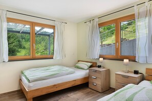 A bedroom with a bed, bedside tables, and a window with curtains.
