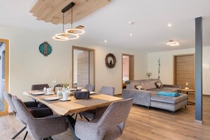 Una sala de estar moderna con comedor, piso de madera y muebles contemporáneos.