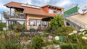 Een tweelaags huis met een balkon, een schotelantenne en een tuin ervoor.