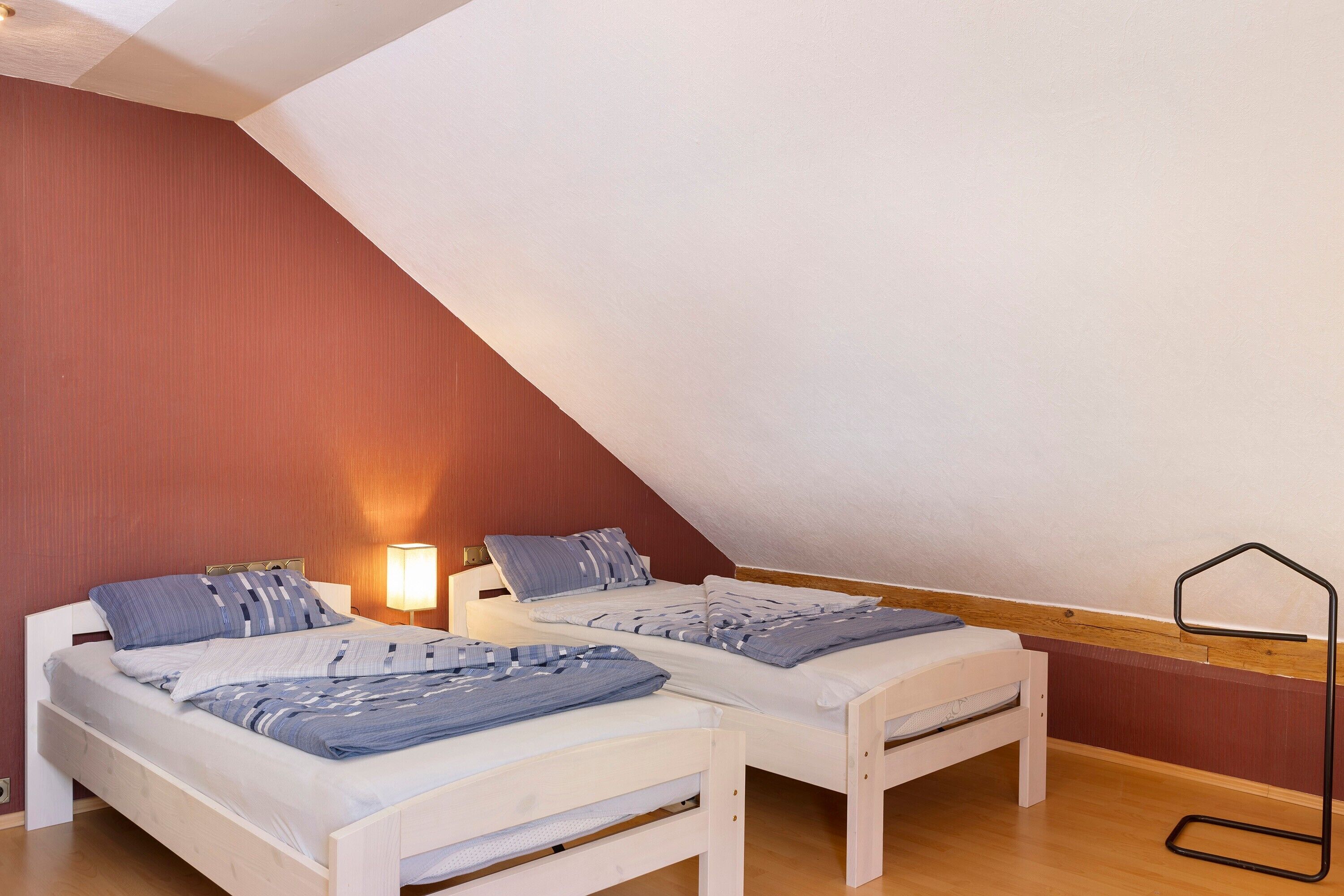 Une chambre avec deux lits, une lampe de table et un lampadaire.
