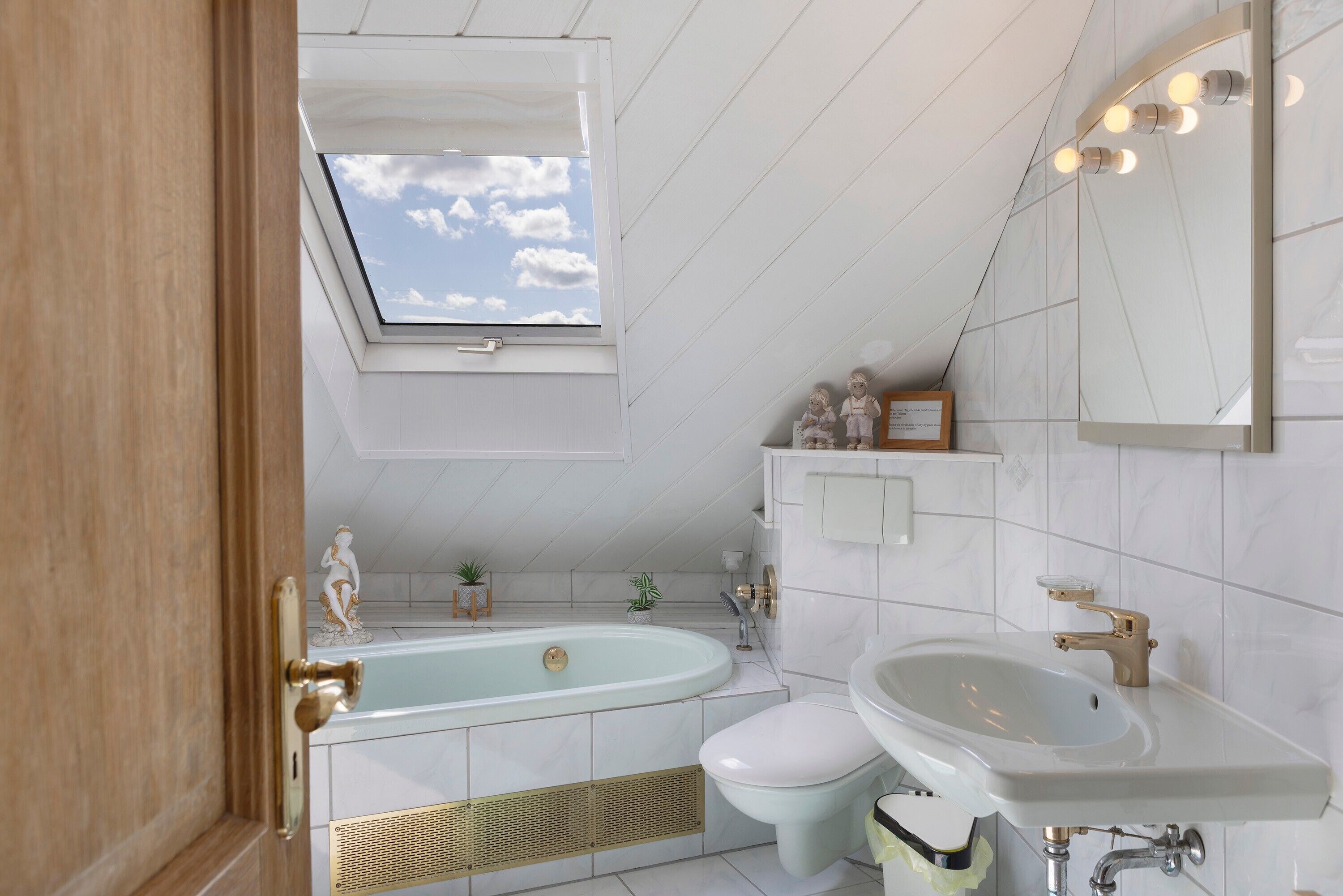Une salle de bain moderne avec un puits de lumière, une baignoire, des toilettes et un lavabo.