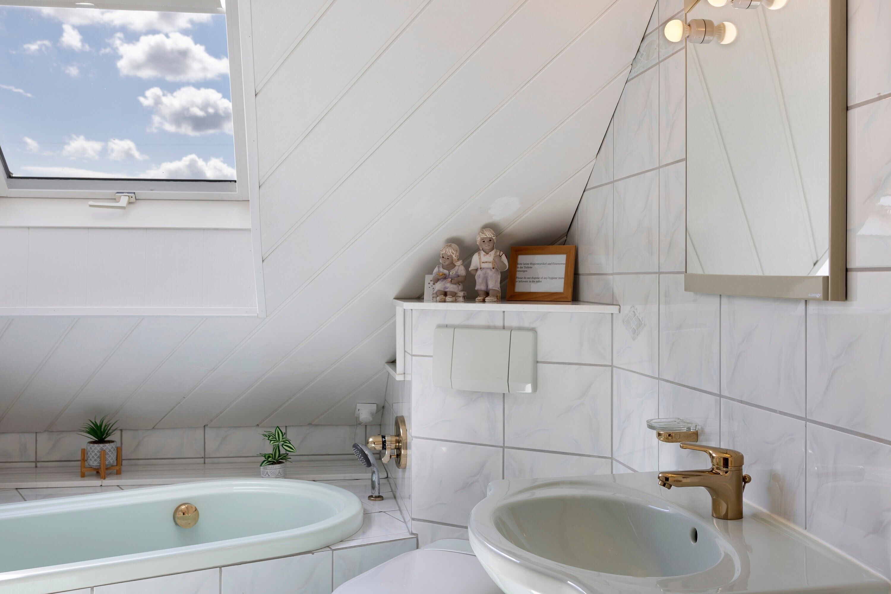 Et moderne badeværelse med skydelugt, badekar, håndvask og underskab.
