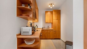 A compact kitchen with wooden cabinets, a microwave, and a sink. - Apartment 'In Der Vulkan-Eifel' with Wi-Fi (Mendig)