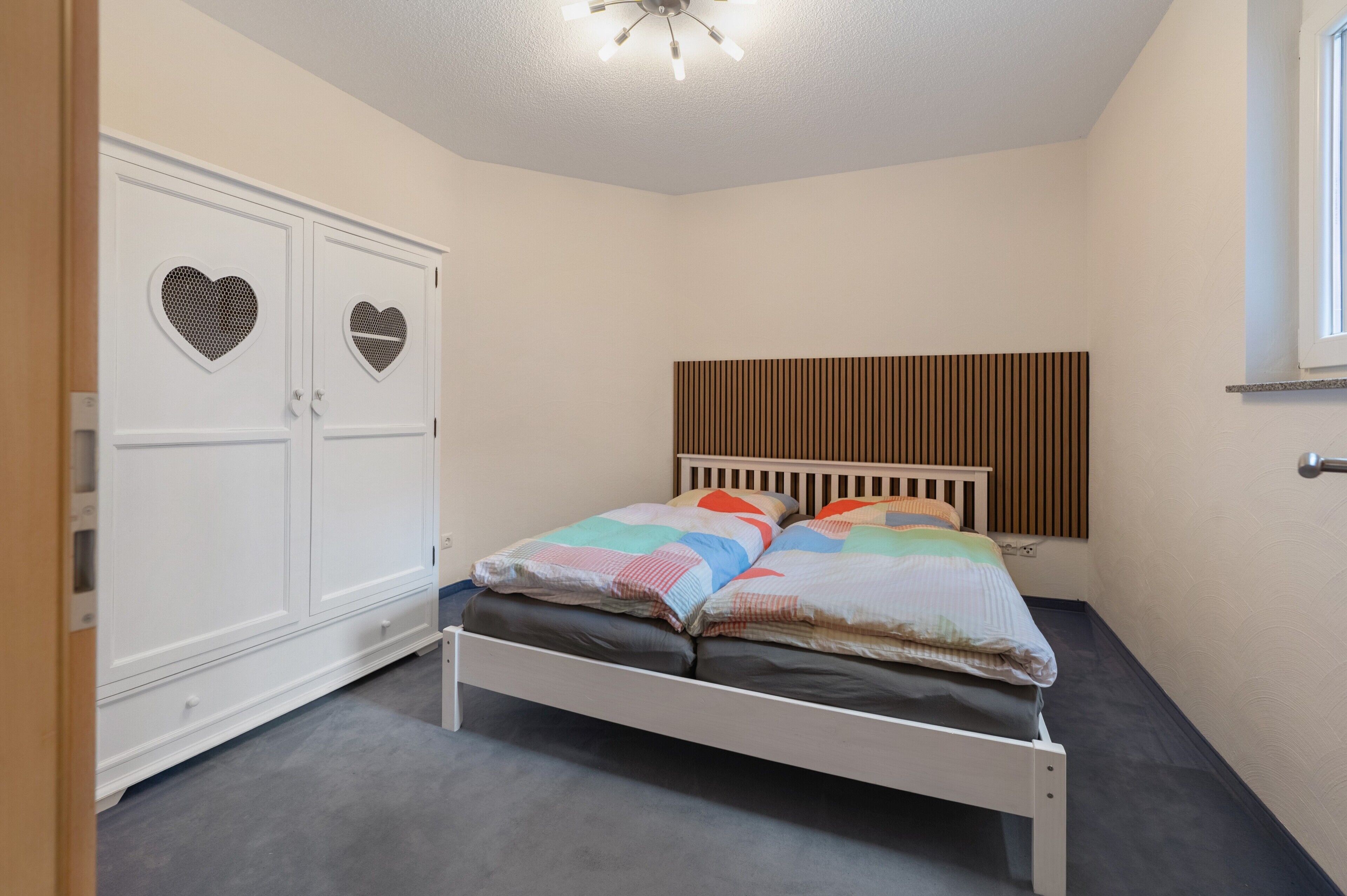 A bedroom with a bed, a wardrobe, and a window.